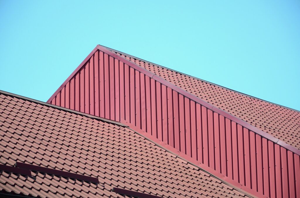 A fragment of a roof from a metal tile of dark red color. Quality Roofing
